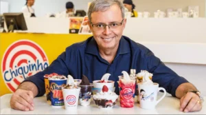 Dono da franquia Chiquinho Sorvetes em uma das lojas com uma variedade de produtos à sua frente.